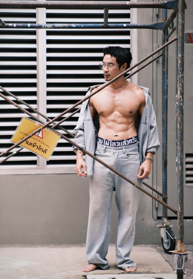 Suriya Danongkhai ในเสื้อเชิ้ตยีนส์เปิดอกยืนหน้านั่งร้าน
